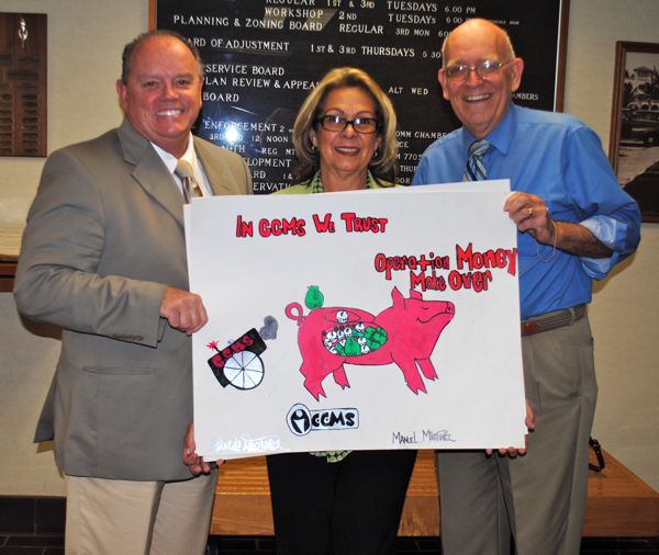 Consumer Credit Management Services execs John Gormley III, Maria Gaitan and Bill Wood hold up a poster drawn by a Village Academy student in support of next month's financial literacy campaign. 