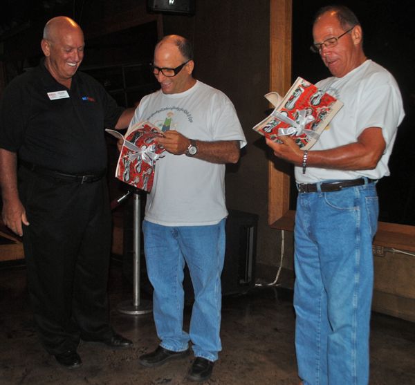 Ron Gilinsky of the Delray Beach Chamber of Commerce presents copies of a book commemorating the Flat Stanley tour to Chuck Halberg and Jimmy Christe. 