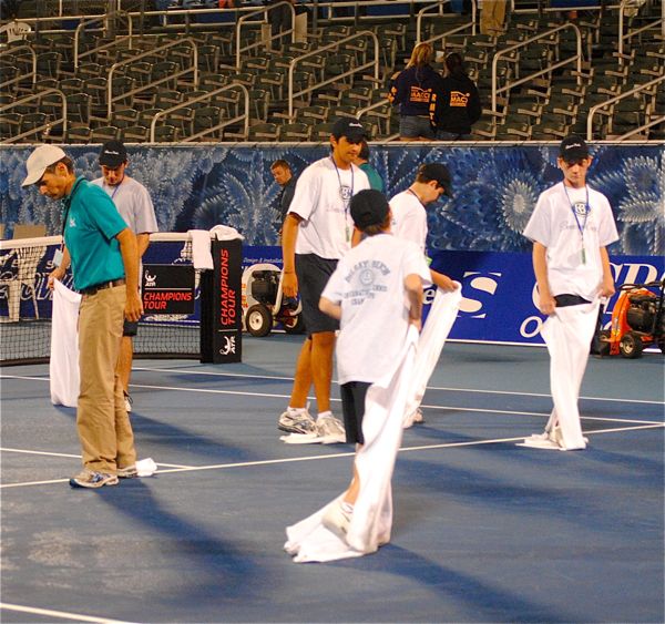 Tournament volunteers dry the court the old fashion way — with bags and bags of towels. 