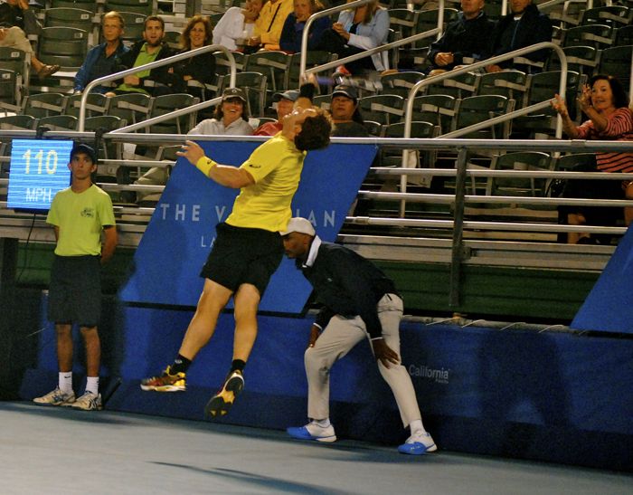 Michael Russell climbs the wall to return a smash from John Isner during their match Tuesday at the Delray Beach Open. 